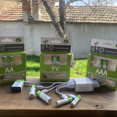 Опаковките AA, AAA и 9V, батерии, кабели и зарядно на дървен перваз