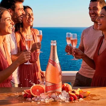 Приятели вдигат чаши с розе кава Perelada Rosé Festival на тераса над морето