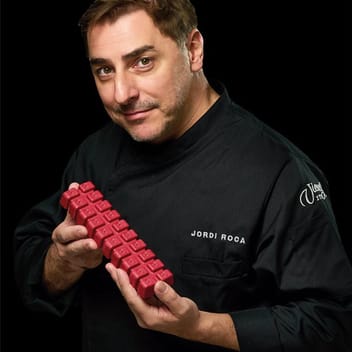 Jordi Roca в черно сако Torrons Vicens, с червено блокче турон в двете ръце