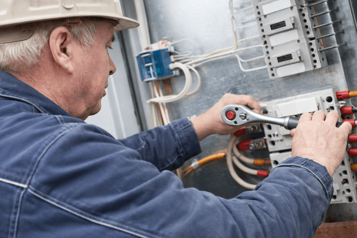 man with contruction cap measuring the electric value with tool