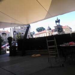 View from beneath the tensile canopy, showing guests seated at the café area under soft daylight.