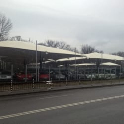 Изглед от улицата към цялата паркинг зона с ромбоидни сенници, автокъща „Капитолия“, София