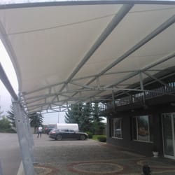 Longitudinal underside view of the textile canopy structure at Sanitex parking zone, showing its full length.